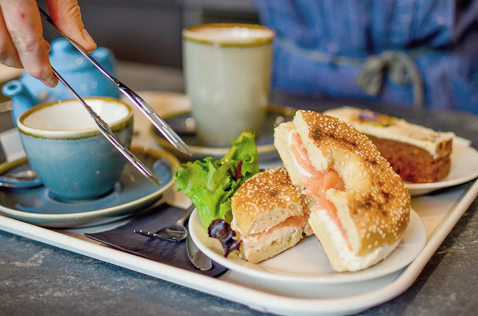 A smoked salmon bagel with salad and a cup of coffee on a café table
