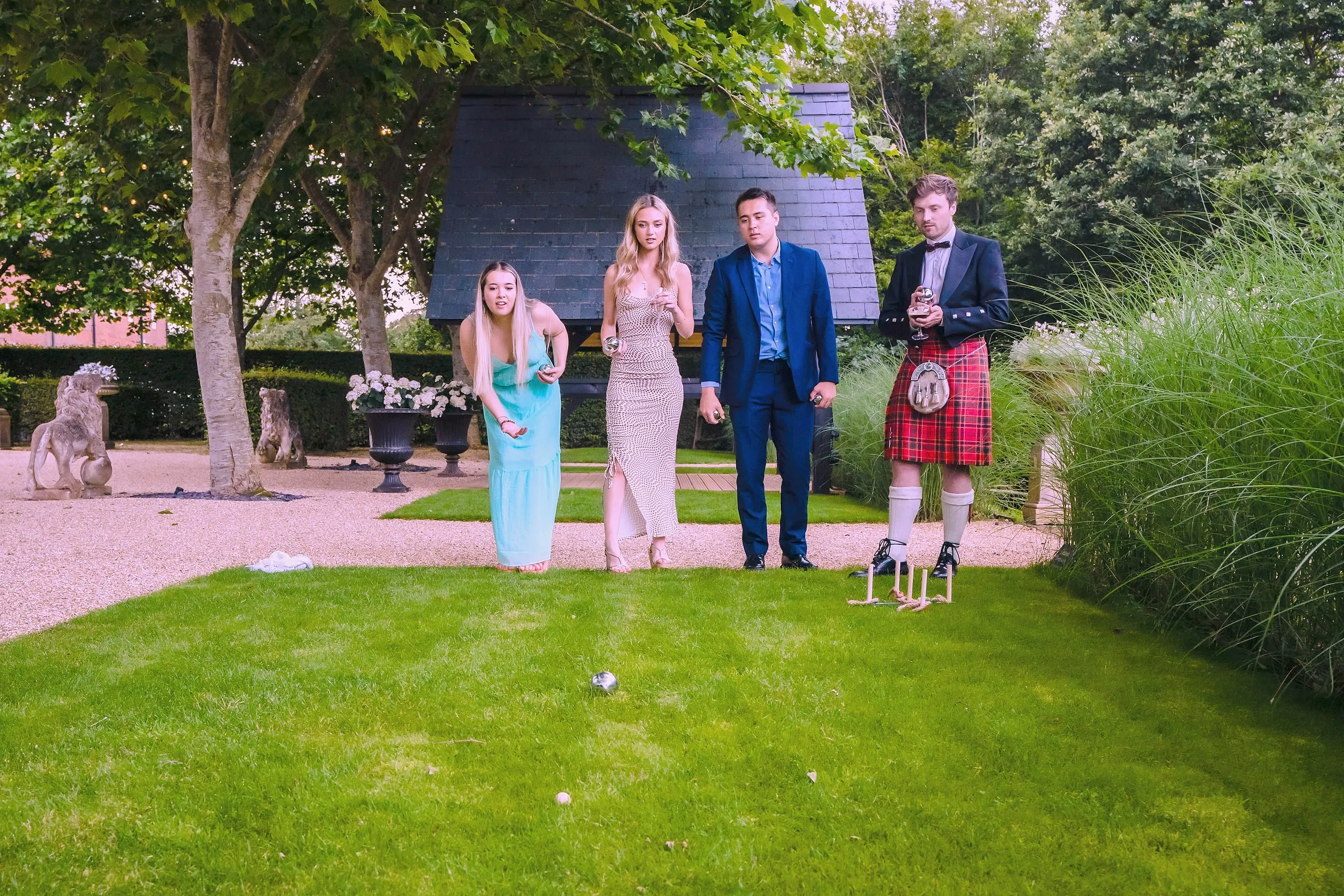 Guests in summer party clothes playing lawn games on the garden grass