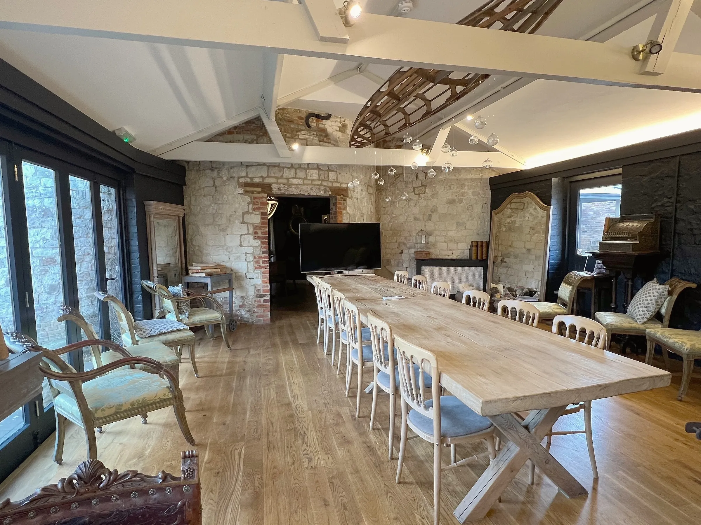 A long wooden table set with chairs in a beamed meeting room with a stone fireplace