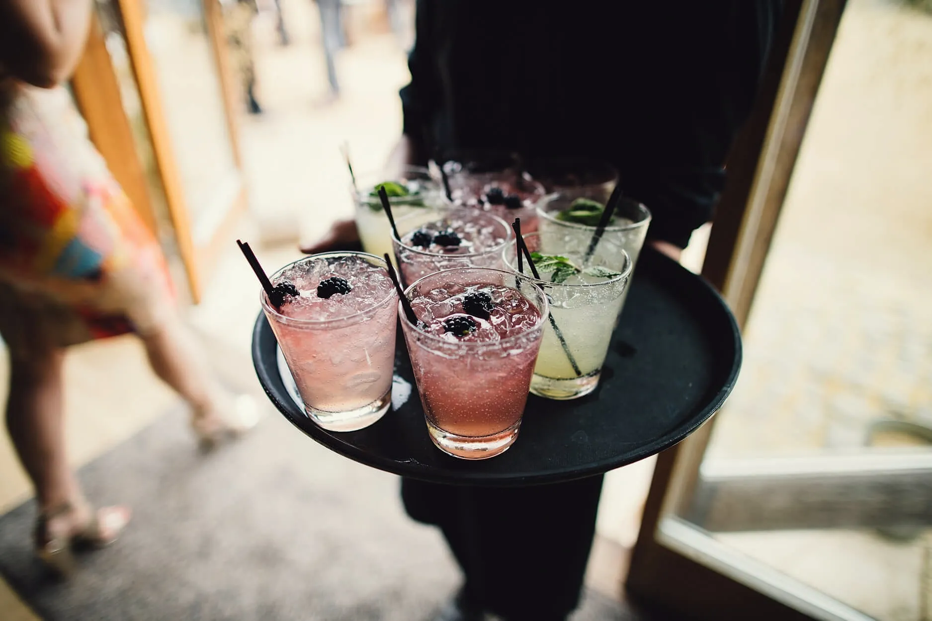 Tray of pink and lime cocktails with blackberries carried out to guests