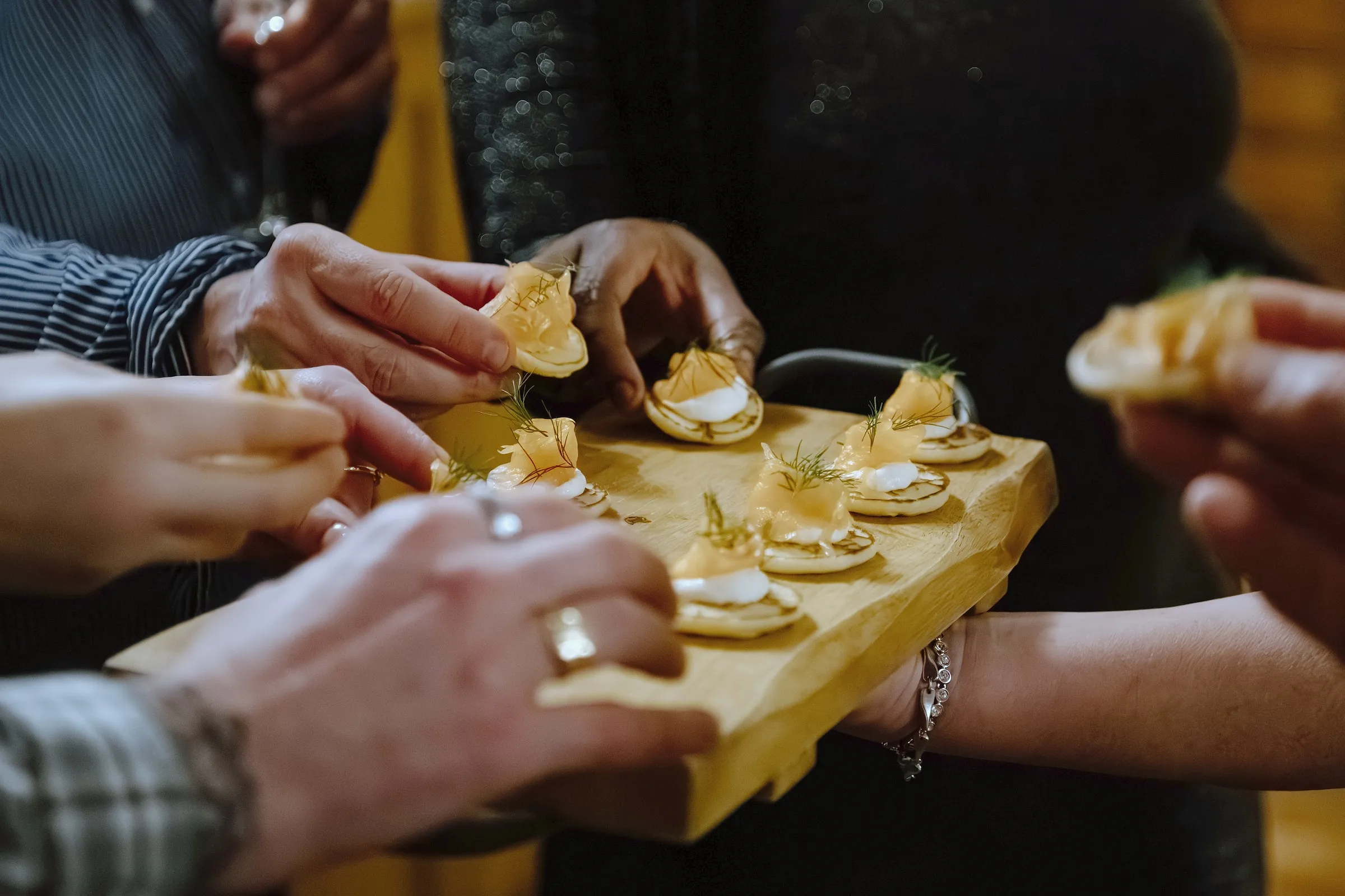 Guests reaching for canapés from a wooden board