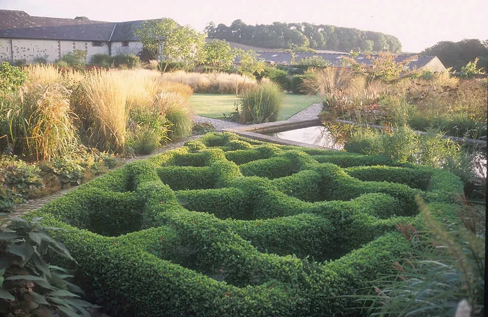 Piet Oudolf's courtyard garden: waves of clipped box among tall grasses, with the barns behind