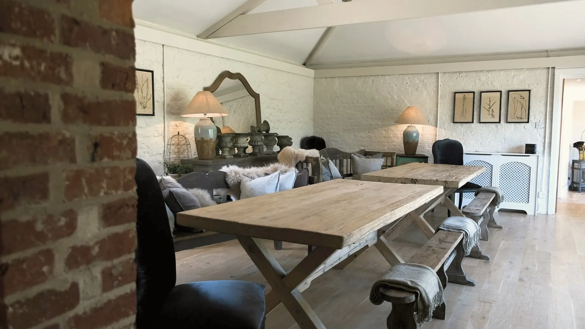 Whitewashed lounge in the Oast House with a long oak table, benches and sofas