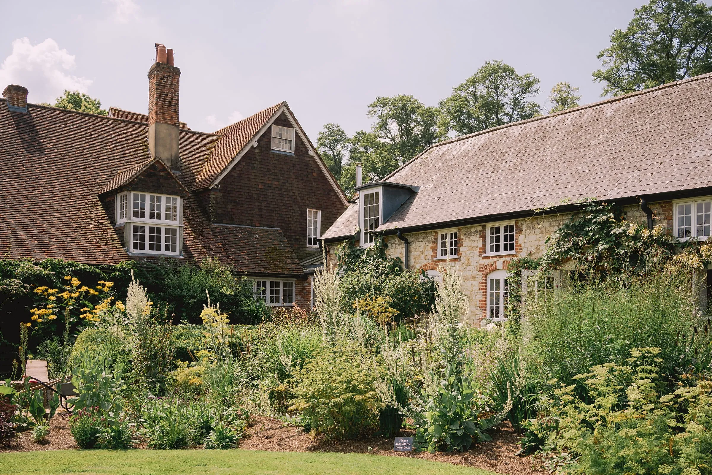 The old flint house and its long garden border in quiet summer light